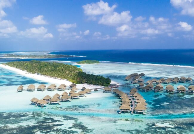 Stunning aerial view of tropical water villas and beaches in the Maldives, showcasing turquoise waters and lush islands.